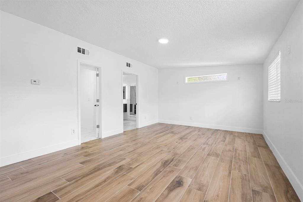 An empty room features white walls, wood-look tile flooring, and two doorways — 1511 E HORATIO AVENUE, MAITLAND, FL