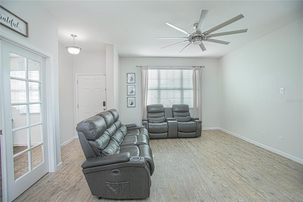 A living room features light wood-look flooring, gray leather reclining furniture, and a ceiling fan — 2427 LINER AVENUE, APOPKA, FL