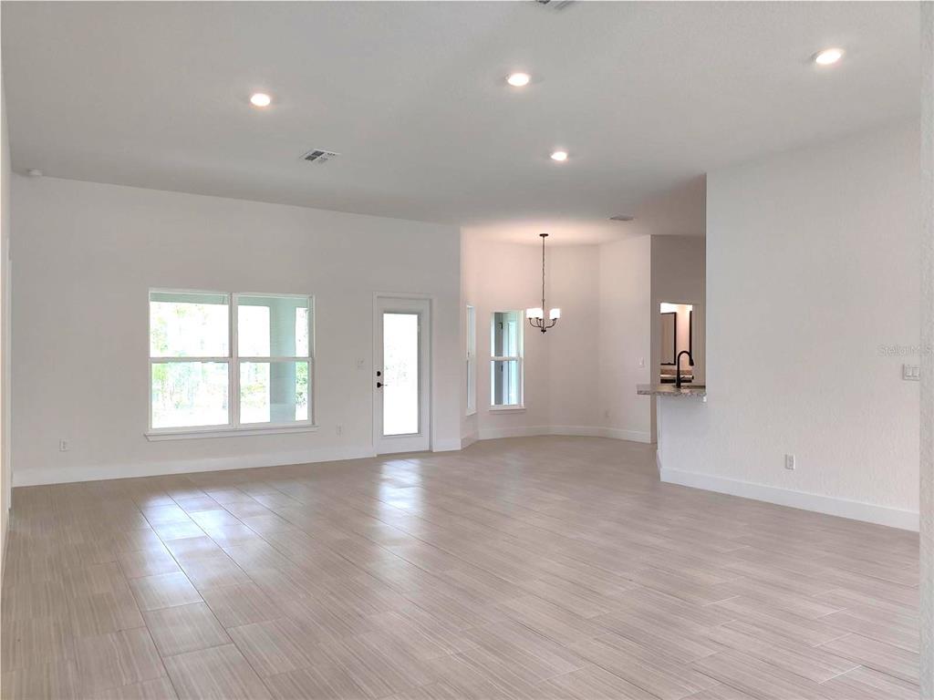 An open-concept living area features light-colored tile flooring, white walls, and recessed lighting — 12275 SCARLET IBIS AVENUE, WEEKI WACHEE, FL