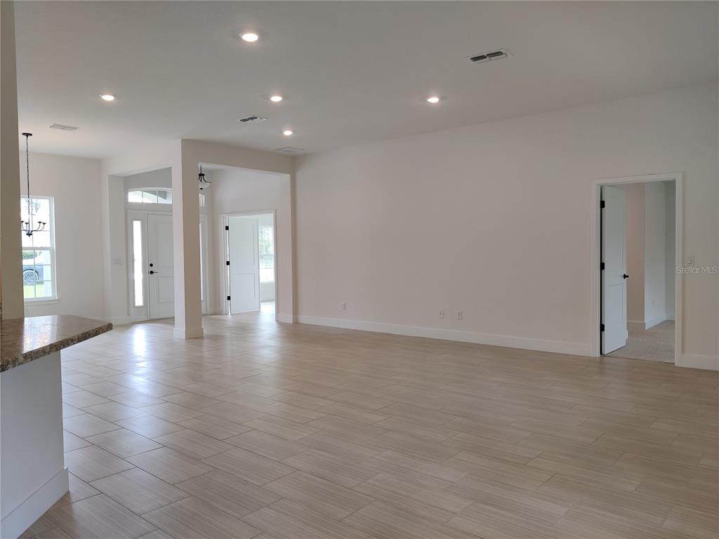 An open-concept living area features light-colored tile flooring, recessed lighting, and white walls — 12275 SCARLET IBIS AVENUE, WEEKI WACHEE, FL