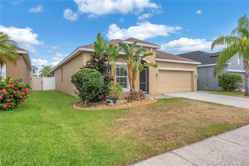A tan single-story house with a two-car garage and a landscaped front yard — 710 PARKER DEN DRIVE, RUSKIN, FL