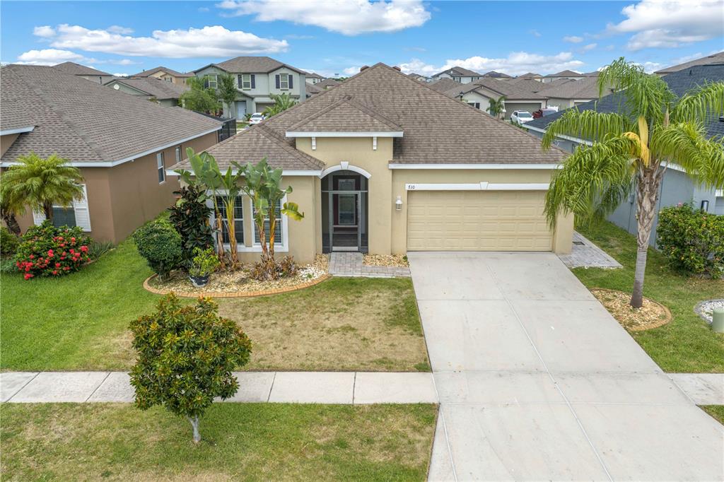A single-story suburban house with a tan stucco exterior, a two-car garage, and a palm tree — 710 PARKER DEN DRIVE, RUSKIN, FL