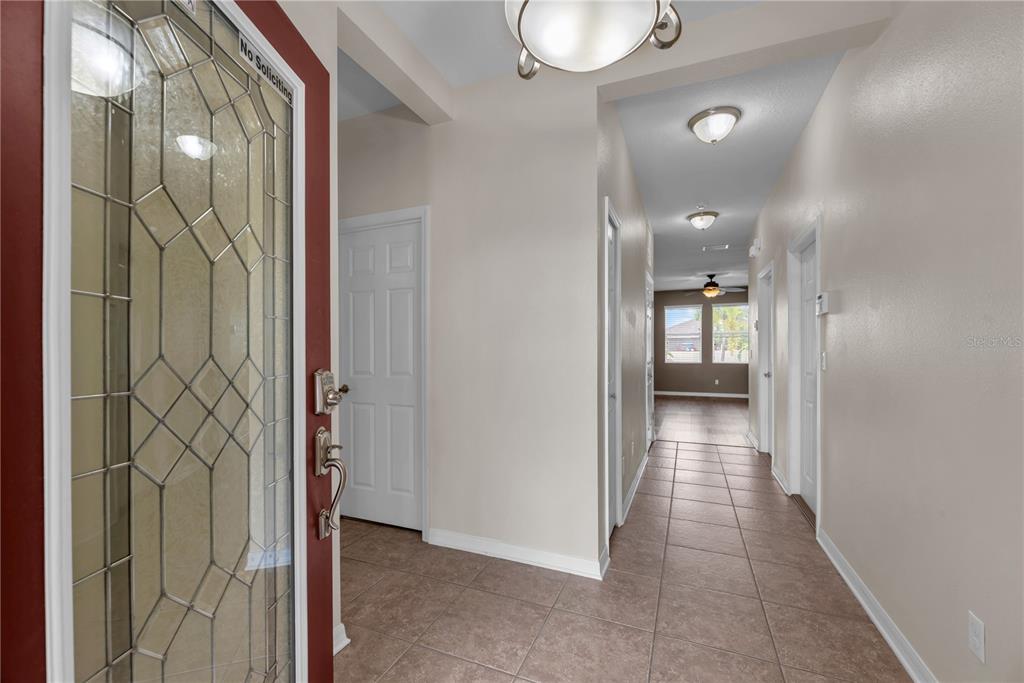 A view from an open front door into a tiled entryway hallway with interior doors — 710 PARKER DEN DRIVE, RUSKIN, FL