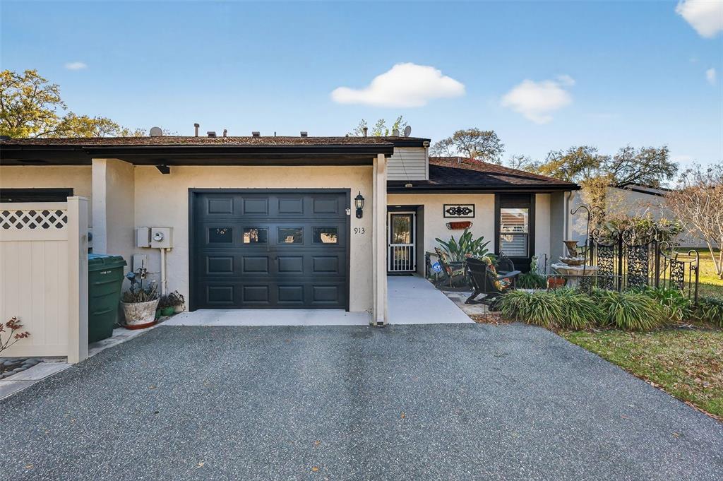 A tan exterior of a residential building with a small patio and landscaped yard — 913 BELLE OAK DRIVE UNIT 0, LEESBURG, FL