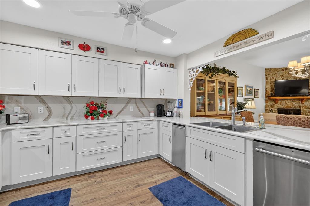 A kitchen with white cabinets, marble-look countertops, stainless steel appliances, and wood-look flooring — 913 BELLE OAK DRIVE UNIT 0, LEESBURG, FL