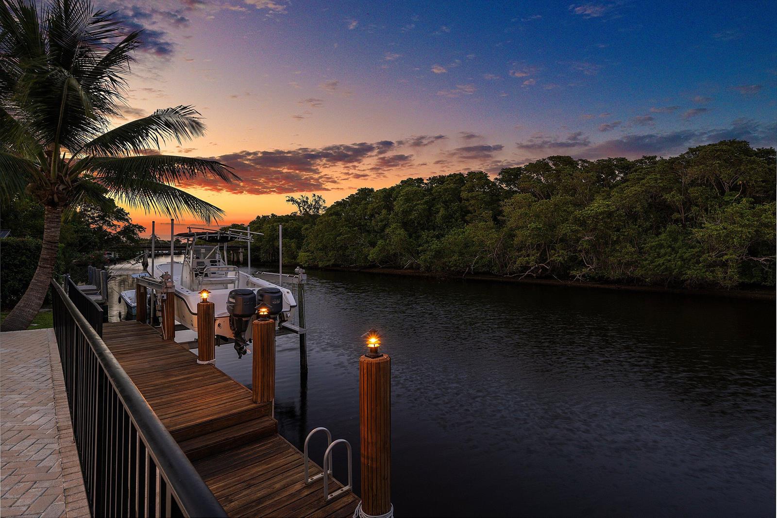 A boat is docked at a wooden pier along a canal at sunset — 763 Camino Lakes Circle, Boca Raton FL 33486, BOCA RATON, FL