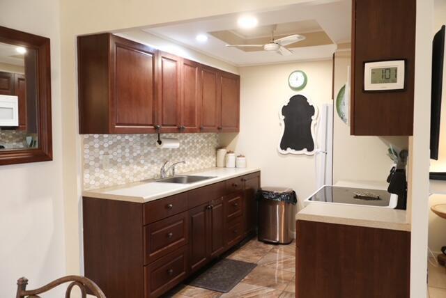 A kitchen features dark wood cabinets, a tiled backsplash, and a stainless steel trash can — 1011 Cornwall A # 1011, Boca Raton FL 33434, BOCA RATON, FL