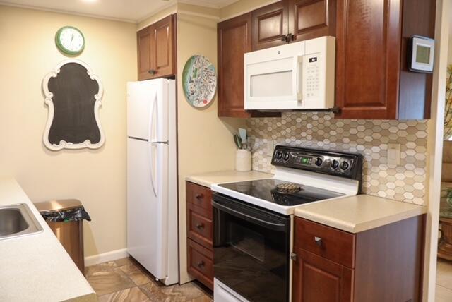 A kitchen features dark wood cabinets, white appliances, a tiled backsplash, and a chalkboard wall — 1011 Cornwall A # 1011, Boca Raton FL 33434, BOCA RATON, FL