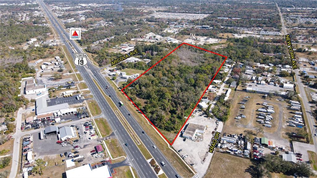 An aerial view shows a large, wooded vacant lot outlined in red next to a highway — 15150 US HIGHWAY 19, HUDSON, FL