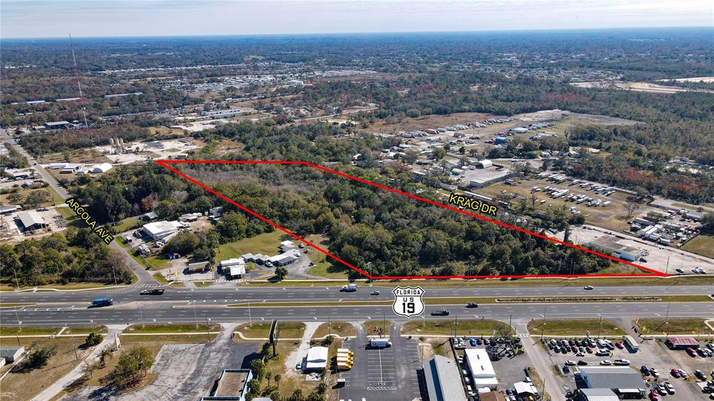An aerial view shows a wooded plot of land outlined in red along a highway — 15150 US HIGHWAY 19, HUDSON, FL