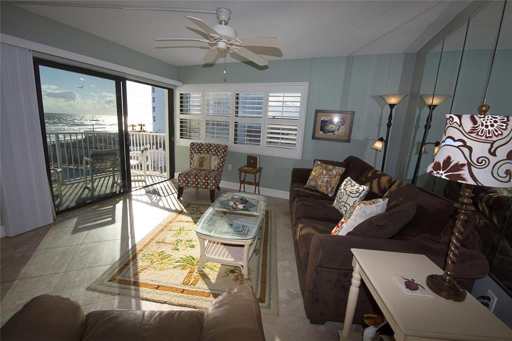 A living room with a brown sofa, glass coffee table, and sliding doors to a balcony — 1571 S ATLANTIC AVENUE UNIT 306, NEW SMYRNA BEACH, FL