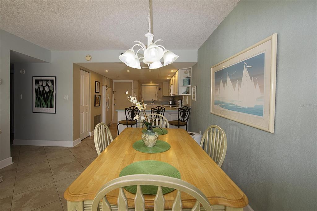 A dining room with a wooden table, chairs, and a chandelier, opening into a kitchen — 1571 S ATLANTIC AVENUE UNIT 306, NEW SMYRNA BEACH, FL