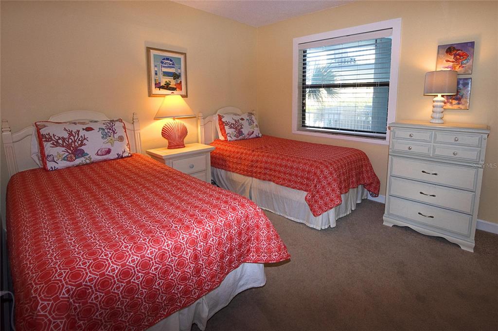 A bedroom features two twin beds with red patterned bedding, a nightstand, and a dresser — 1571 S ATLANTIC AVENUE UNIT 306, NEW SMYRNA BEACH, FL