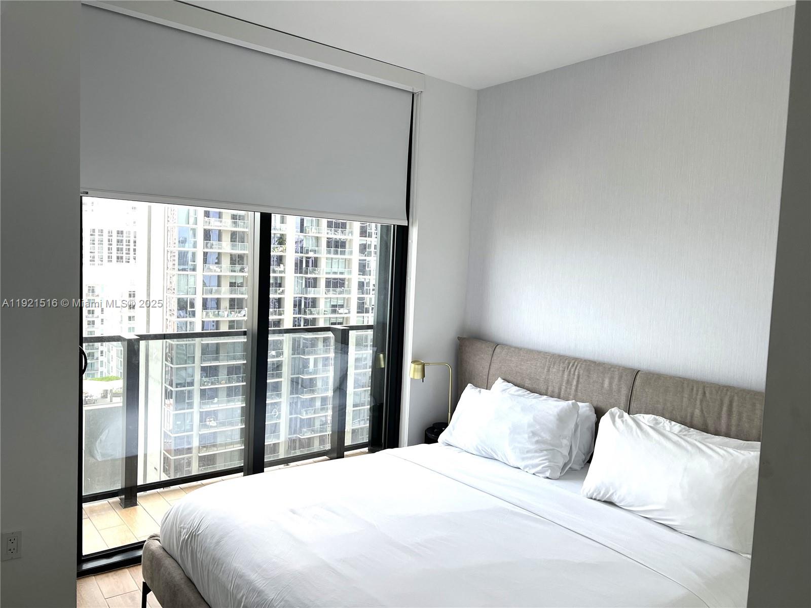 A bedroom features a bed with white linens, a grey headboard, and a balcony view — 398 NE 5th St # 2215, Miami FL 33132, MIAMI, FL