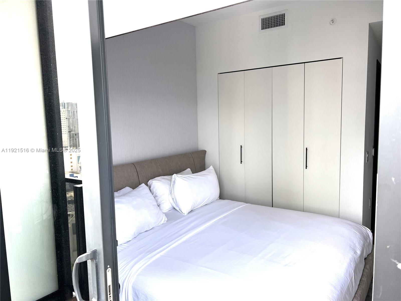 A bedroom features a bed with white linens, a gray headboard, and white closet doors — 398 NE 5th St # 2215, Miami FL 33132, MIAMI, FL