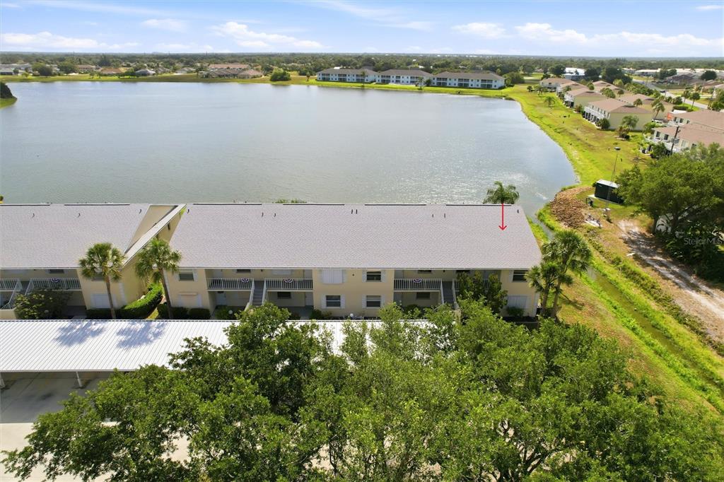 An aerial view shows a multi-story apartment building situated next to a large lake — 1512 RIO DE JANEIRO AVENUE UNIT 428, PUNTA GORDA, FL