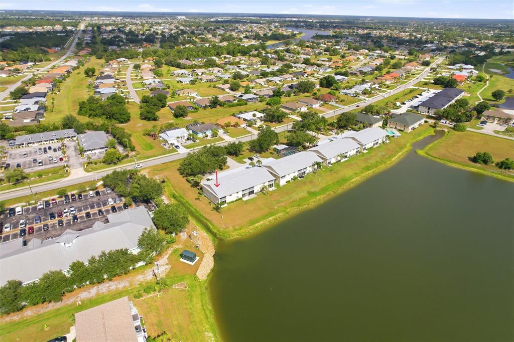 An aerial view shows a multi-unit residential building with a red arrow pointing toward it — 1512 RIO DE JANEIRO AVENUE UNIT 428, PUNTA GORDA, FL