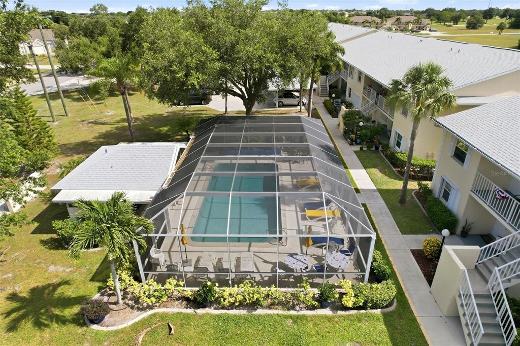 An aerial view shows a screened-in swimming pool area next to a multi-story apartment building — 1512 RIO DE JANEIRO AVENUE UNIT 428, PUNTA GORDA, FL