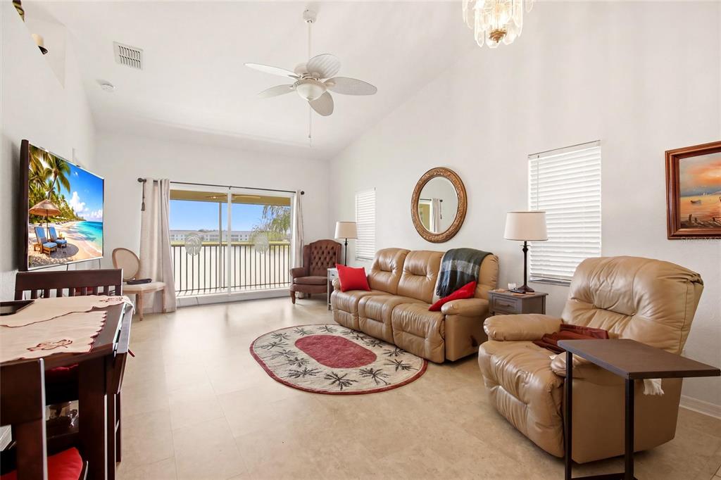 A living room with beige leather furniture, a round rug, and a view of water — 1512 RIO DE JANEIRO AVENUE UNIT 428, PUNTA GORDA, FL