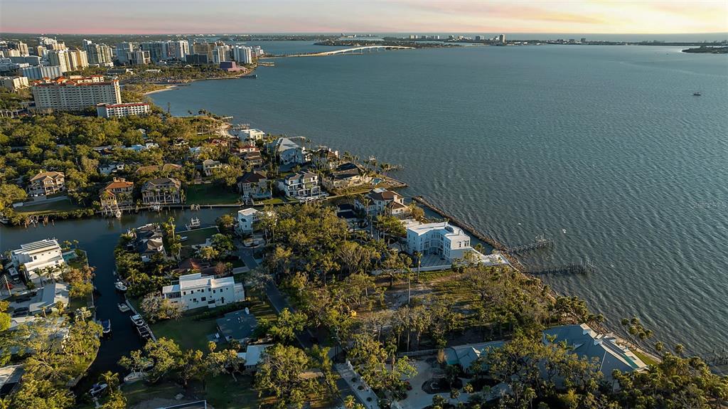 An aerial view of a waterfront neighborhood with large homes, dense trees, and a bridge — 2043 ALAMEDA AVENUE, SARASOTA, FL
