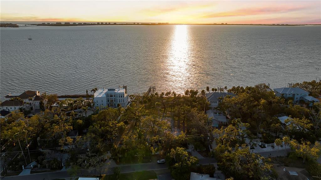 An aerial view shows waterfront homes surrounded by trees along a bay at sunset — 2043 ALAMEDA AVENUE, SARASOTA, FL