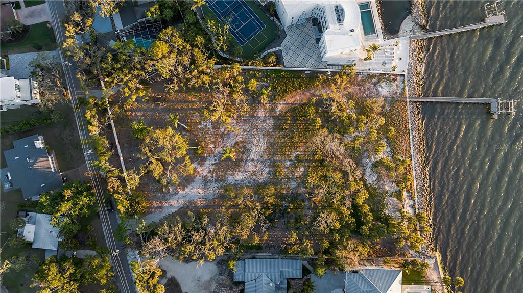 An aerial view shows a vacant waterfront lot with trees and a private wooden dock — 2043 ALAMEDA AVENUE, SARASOTA, FL