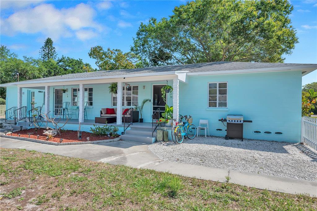 A light blue single-story house features a covered front porch, gravel yard, and two bicycles — 5025 28TH AVENUE S, GULFPORT, FL