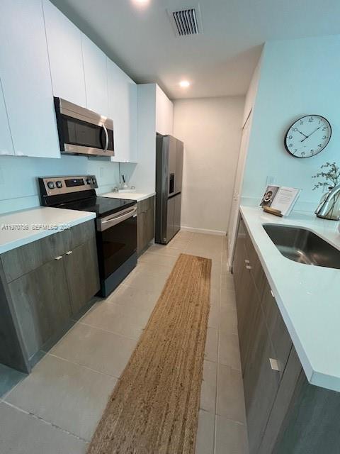 A galley kitchen features light wood cabinets, stainless steel appliances, and a long runner rug — 2526 Pierce St # 12, Hollywood FL 33020, HOLLYWOOD, FL