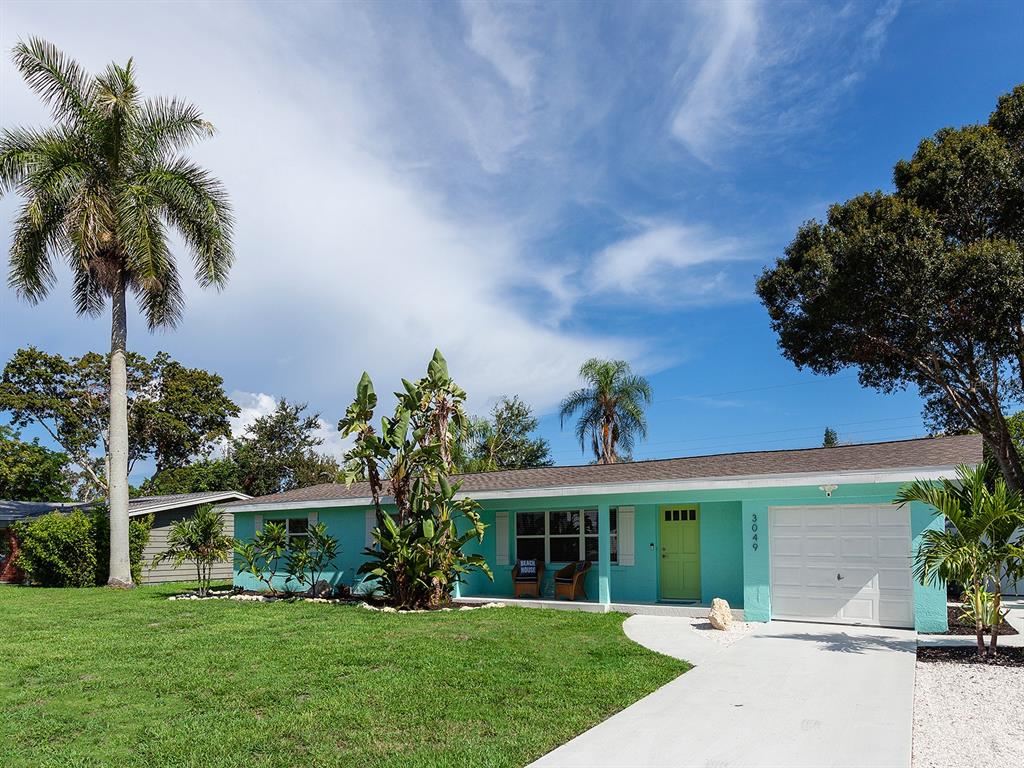 A single-story turquoise house with a white garage door, a palm tree, and a lawn — 3049 WOOD STREET, SARASOTA, FL