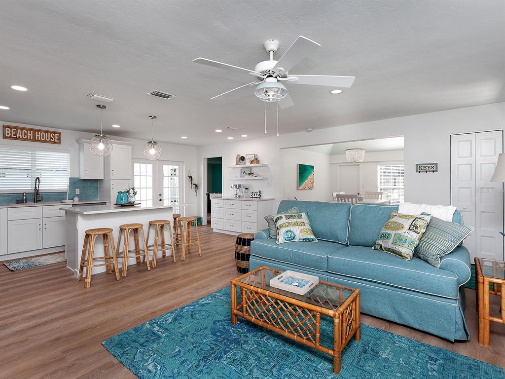 An open-concept living room and kitchen feature a blue sofa, rattan coffee table, and island — 3049 WOOD STREET, SARASOTA, FL