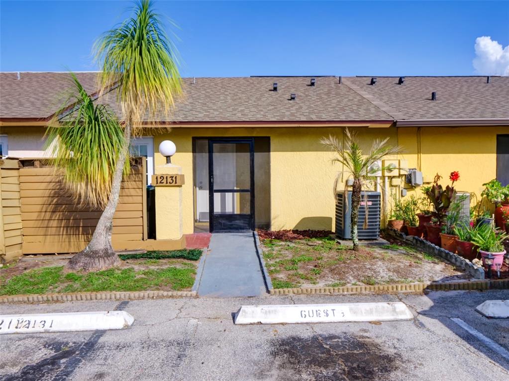 A yellow single-story residential unit features a screen door, a palm tree, and guest parking — 12131 SAND PEBBLE WAY, ORLANDO, FL