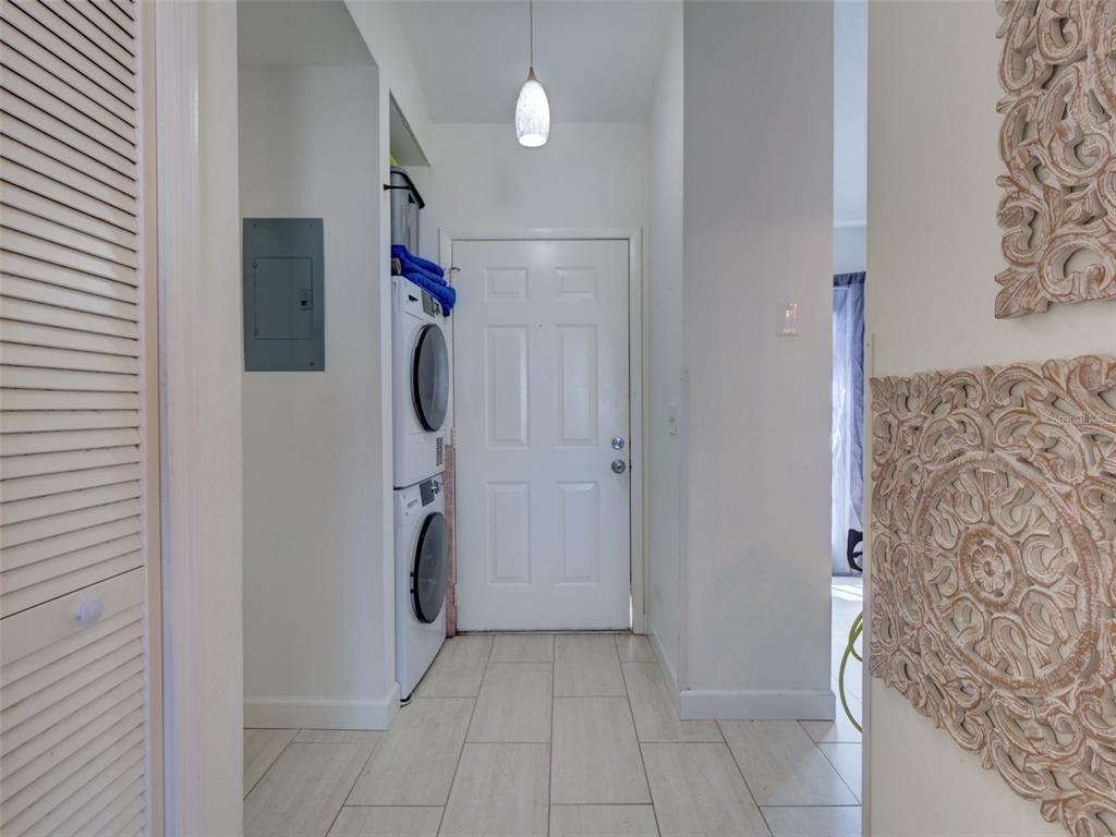A laundry area features a stacked washer and dryer set next to a white door — 12131 SAND PEBBLE WAY, ORLANDO, FL