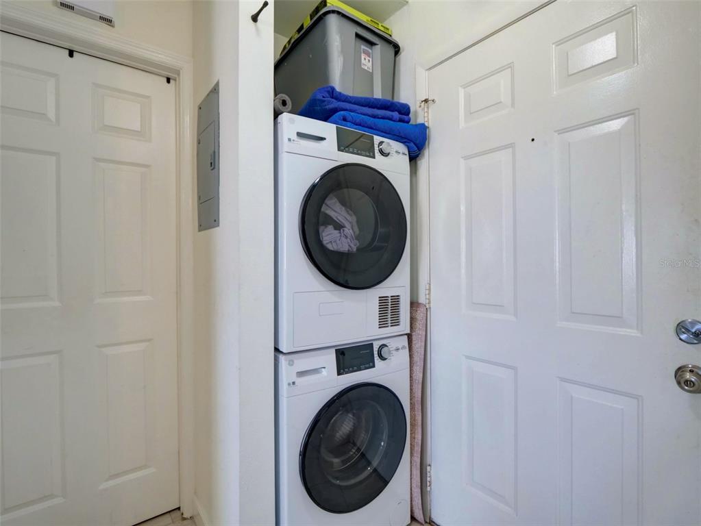 A stacked washer and dryer unit sits in a small laundry closet between two doors — 12131 SAND PEBBLE WAY, ORLANDO, FL