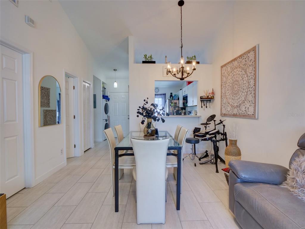 A dining area with a glass table, white chairs, and a drum set nearby — 12131 SAND PEBBLE WAY, ORLANDO, FL