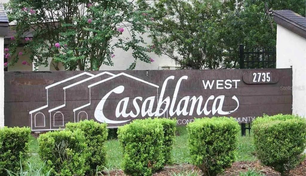 A brown wooden sign for Casablanca West Community stands in front of green bushes — 2735 SW 35 PLACE UNIT 1607, GAINESVILLE, FL