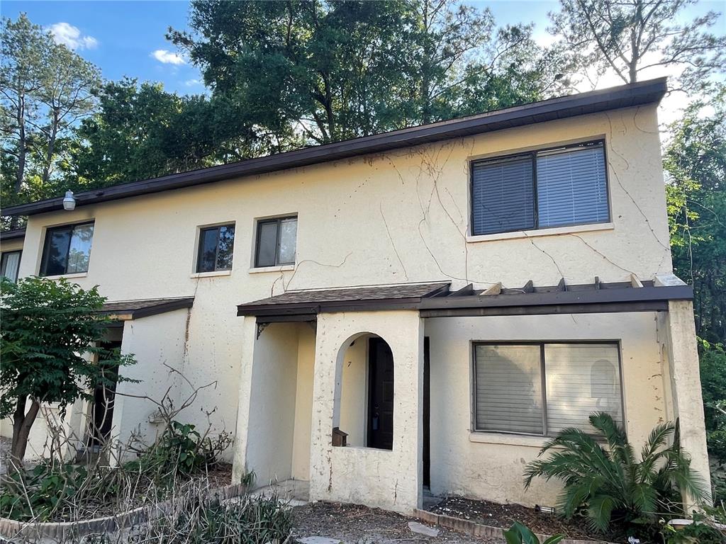 The exterior of a two-story stucco townhouse features a covered entryway and a pergola — 2735 SW 35 PLACE UNIT 1607, GAINESVILLE, FL