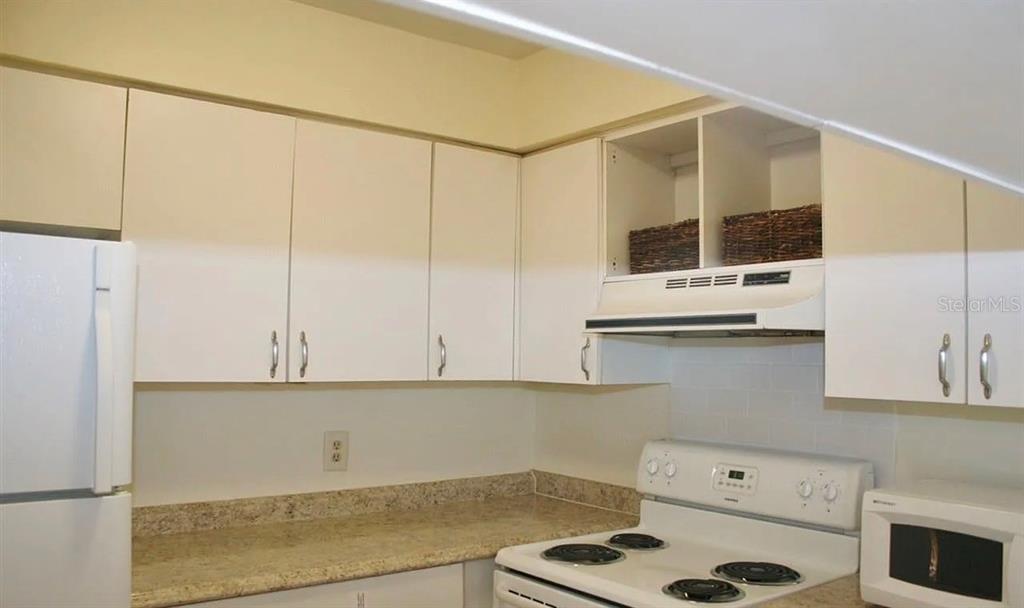 A kitchen features white cabinets, a speckled countertop, a white stove, and a microwave — 2735 SW 35 PLACE UNIT 1607, GAINESVILLE, FL