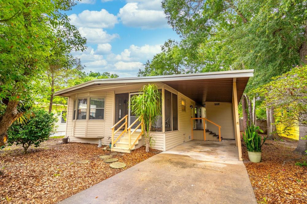 A single-story mobile home with a screened-in porch, carport, and beige siding under trees — 508 W PLANTATION BOULEVARD, LAKE MARY, FL