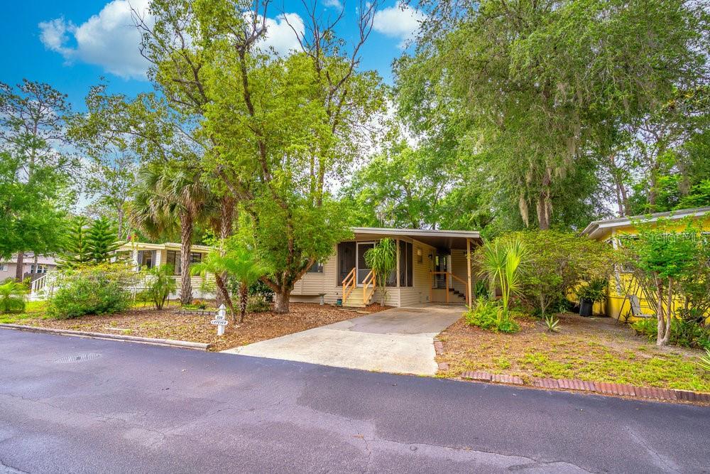A single-story mobile home with a screened porch and concrete driveway sits under large trees — 508 W PLANTATION BOULEVARD, LAKE MARY, FL