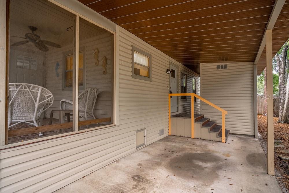 A concrete patio area features a screened-in porch, beige siding, and stairs with yellow railings — 508 W PLANTATION BOULEVARD, LAKE MARY, FL