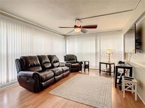 A living room features a brown leather sofa, a matching recliner, and light wood flooring — 4780 COVE CIRCLE UNIT 101, ST PETERSBURG, FL