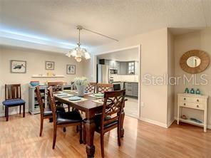 A dining room features a wooden table with chairs, a chandelier, and a kitchen view — 4780 COVE CIRCLE UNIT 101, ST PETERSBURG, FL