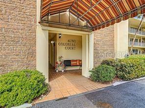 The entrance to a building features a striped awning over a brick-walled walkway and bench — 4780 COVE CIRCLE UNIT 101, ST PETERSBURG, FL