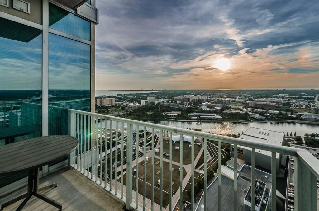 A high-rise balcony overlooks a city park, a river, and a sunset over the horizon — 777 N ASHLEY DRIVE UNIT 2403, TAMPA, FL