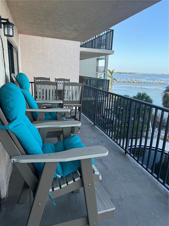 A balcony features several gray Adirondack chairs with bright blue cushions overlooking a bay — 9 TURNER STREET UNIT 11, CLEARWATER, FL