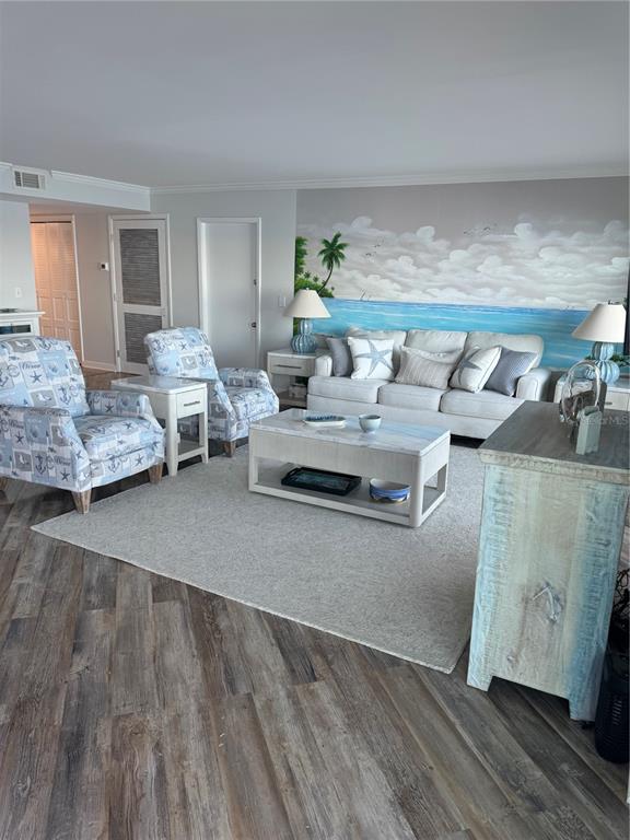 A living room features a beach-themed mural, light-colored furniture, and wood-look flooring — 9 TURNER STREET UNIT 11, CLEARWATER, FL