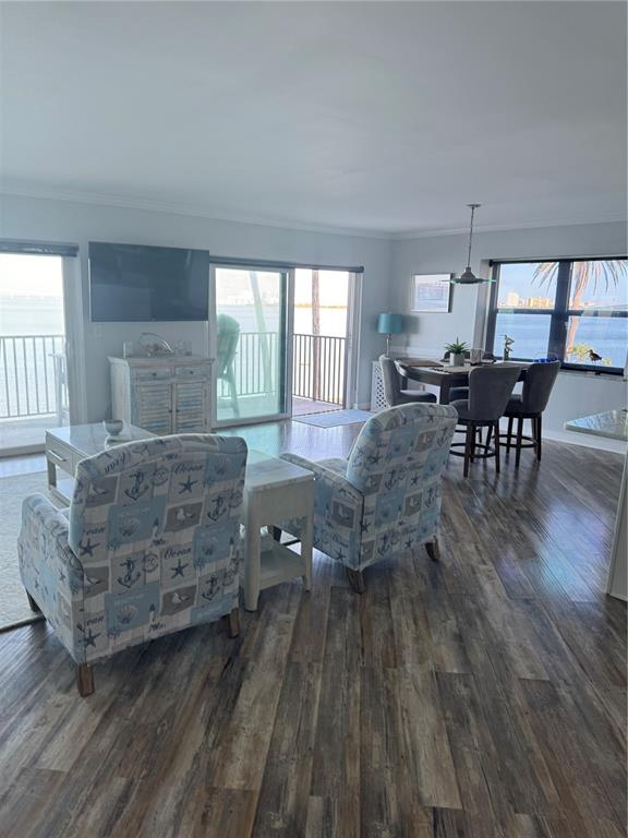 A living and dining area features coastal-themed armchairs, wood-look flooring, and views of the water — 9 TURNER STREET UNIT 11, CLEARWATER, FL