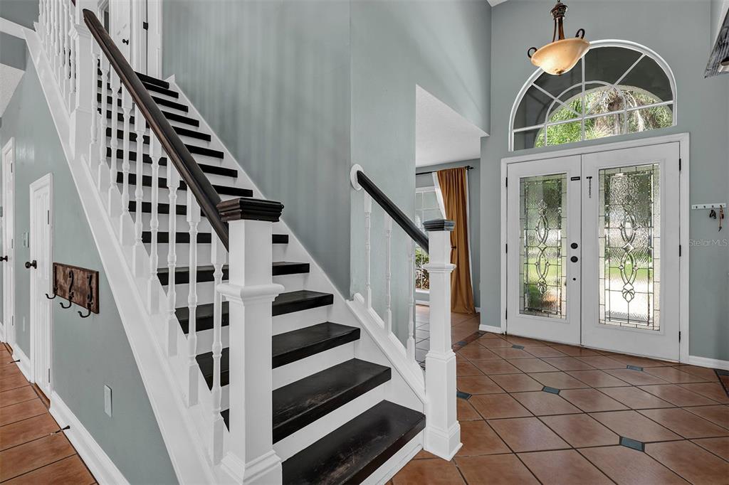An entryway features a dark wood staircase, tile flooring, and a double front door — 601 RED MAPLE COURT, OVIEDO, FL