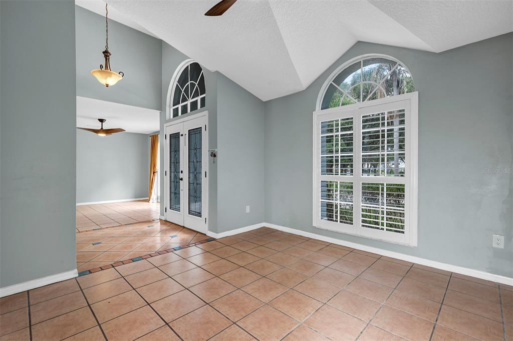A room with light blue walls, tile flooring, a vaulted ceiling, and a large arched window — 601 RED MAPLE COURT, OVIEDO, FL