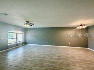 A spacious room features light-colored tile flooring, a ceiling fan, and a large arched window — 22 PLATEAU LANE UNIT B, PALM COAST, FL